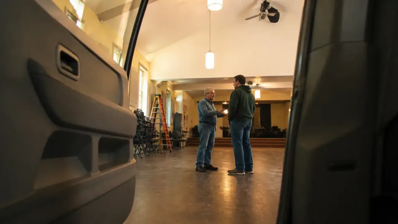 Low angle of a marked accessible parking space with two staff talking nearby