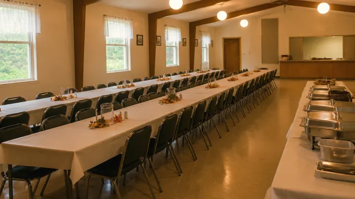 Long tables and rows of chairs set for a meal in a church fellowship hall