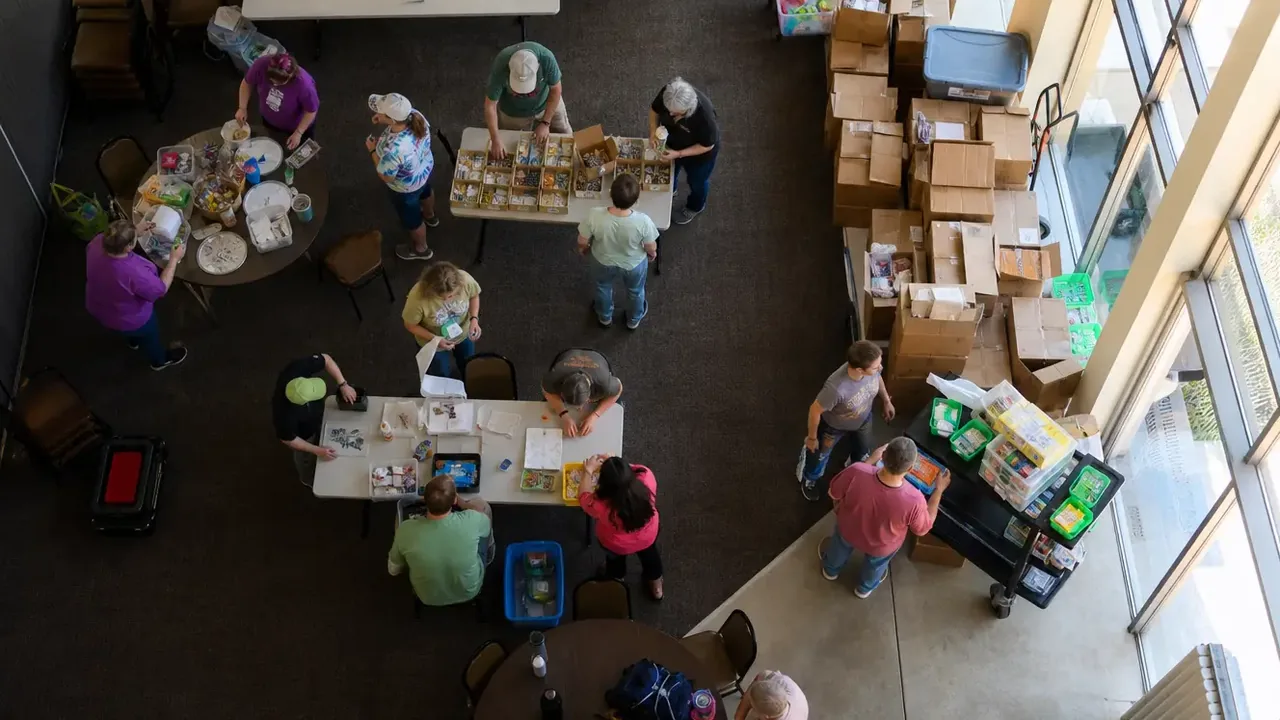 Overhead view of people sorting supplies at tables beside boxes and storage tubs
